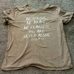 A tan shirt with a Bible verse on it Joshua 1:9